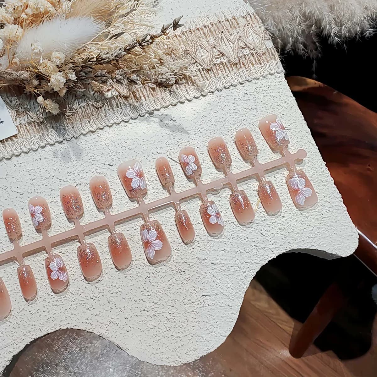 Korte ovale press-on negle med fransk tip, glitter og blomsterdesign